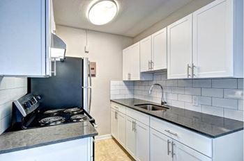 A kitchen with white cabinets and a black stove top.